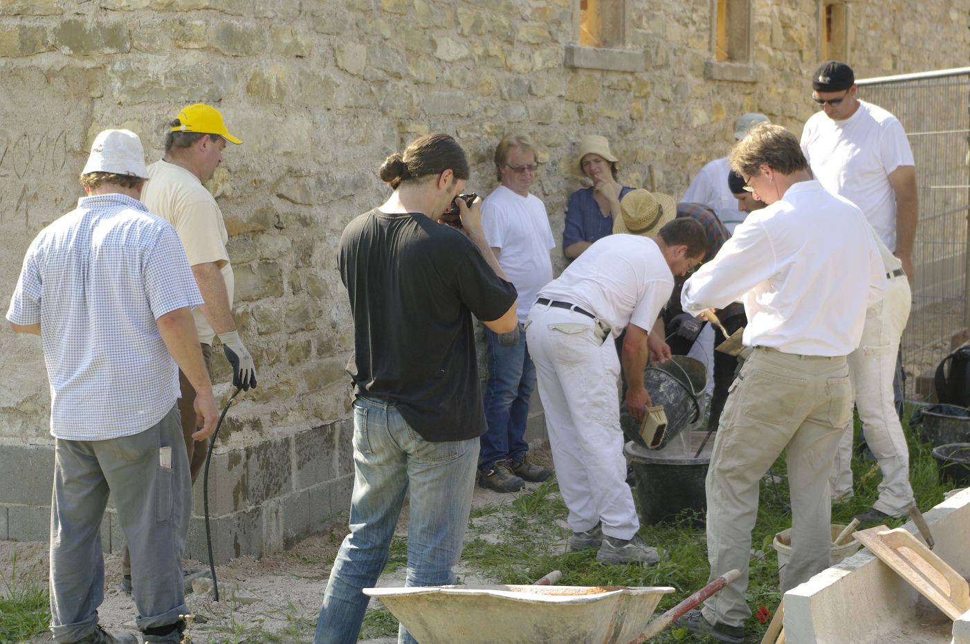 Eine Gruppe Menschen rührt Putz an. Der Putz wird für Wände hergestellt.