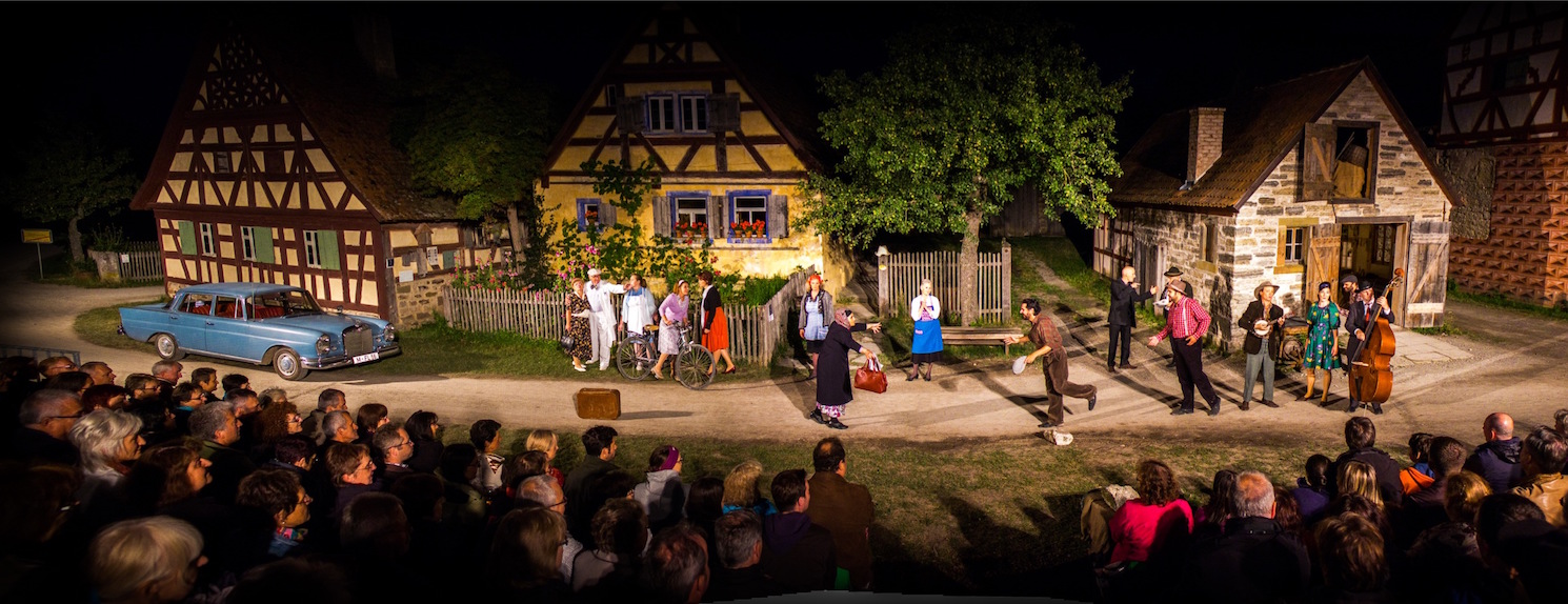 Theaterszene vor drei Häusern des Freilandmuseums