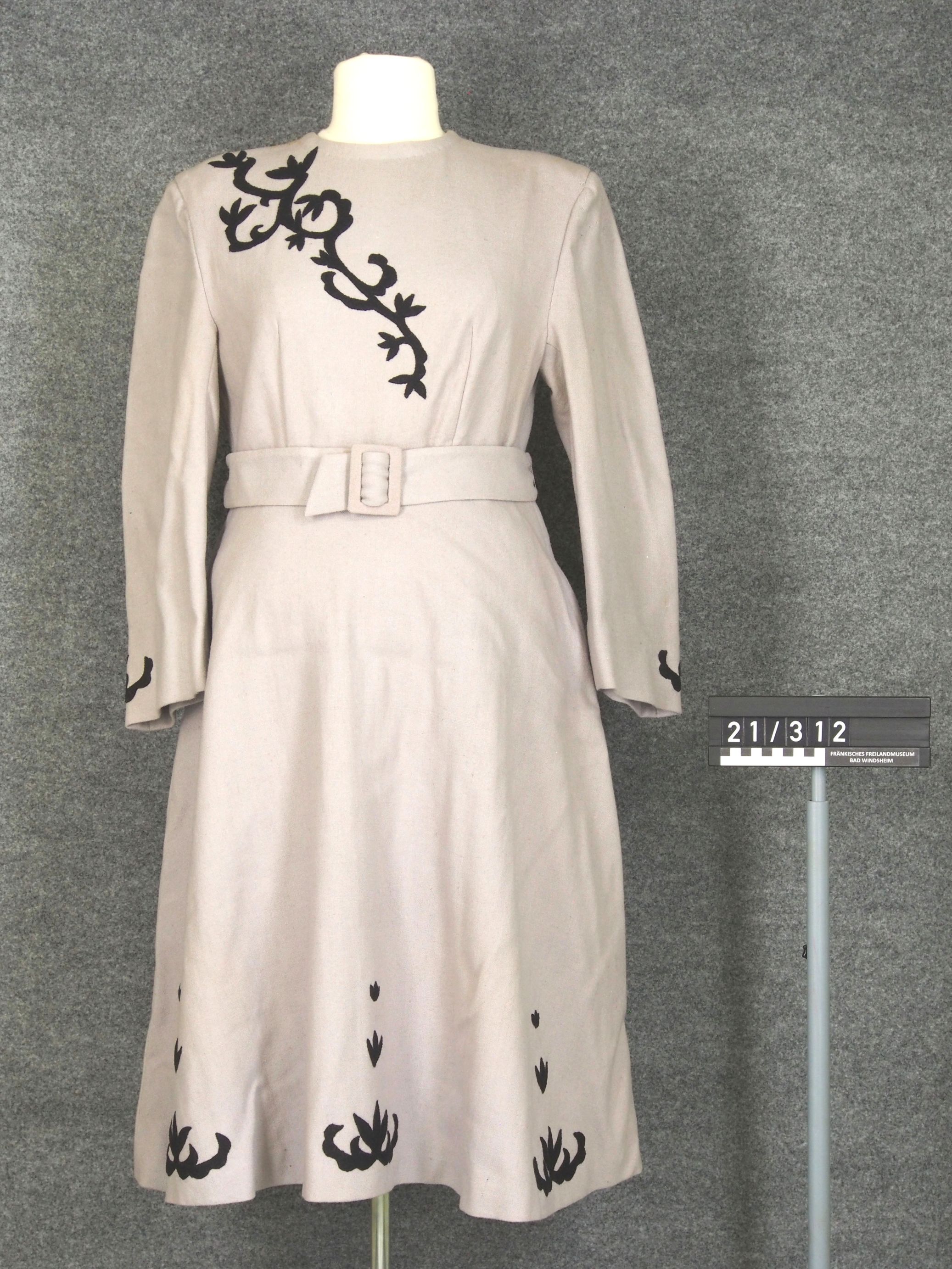 Das Winterkleid ist weiß. Auf der Brust ist ein schwarzer Zweig. Unten sind Blätter. Um die Taille ist ein Band.