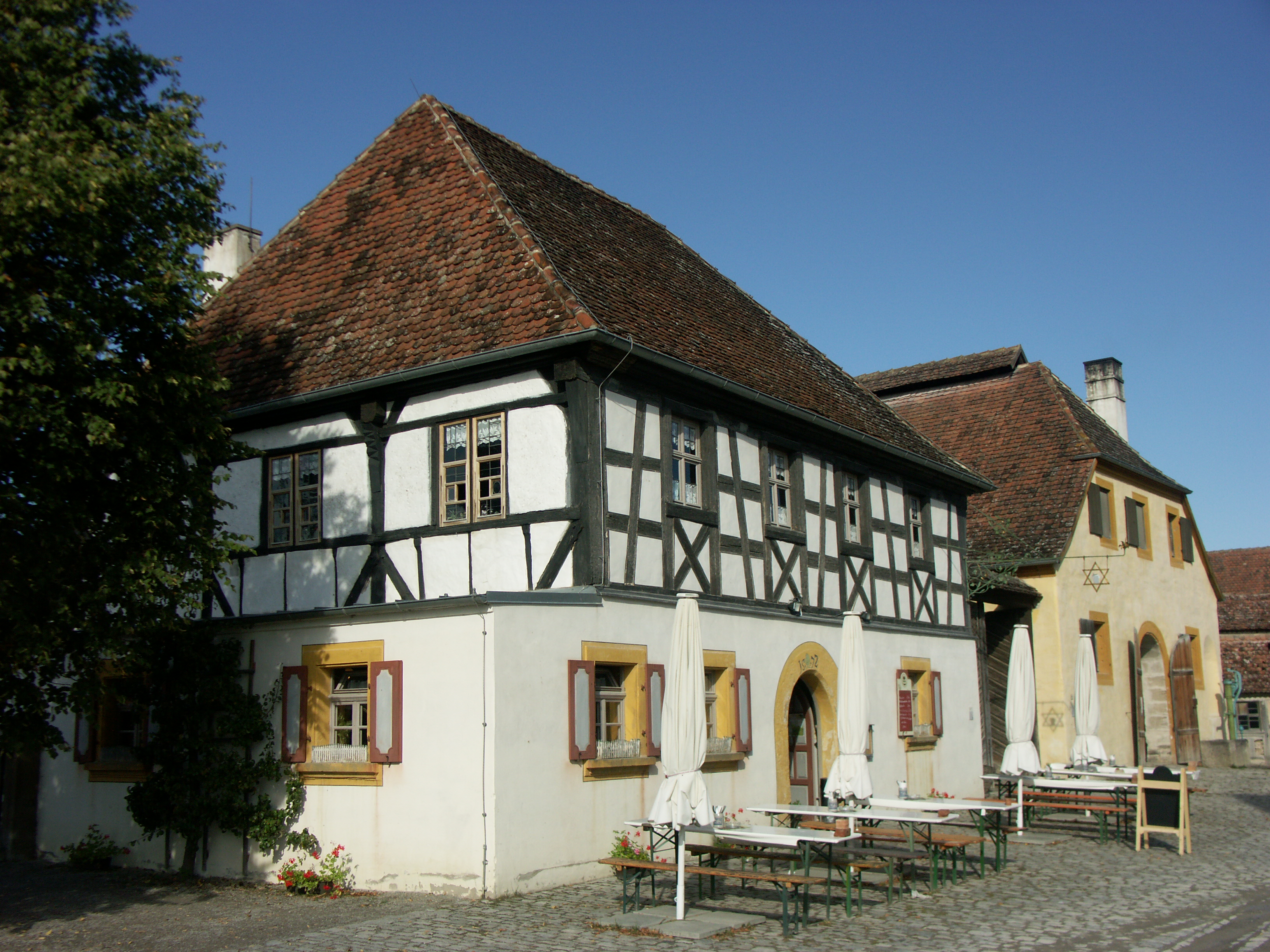 FFM_Gashaus aus Mühlhausen Ein niedriges, zweigeschössiges Gasthaus mit Fachwerk im OG und markantem, rundbogigem, gelbem Türbogen, direkt neben der Kommunbrauerei